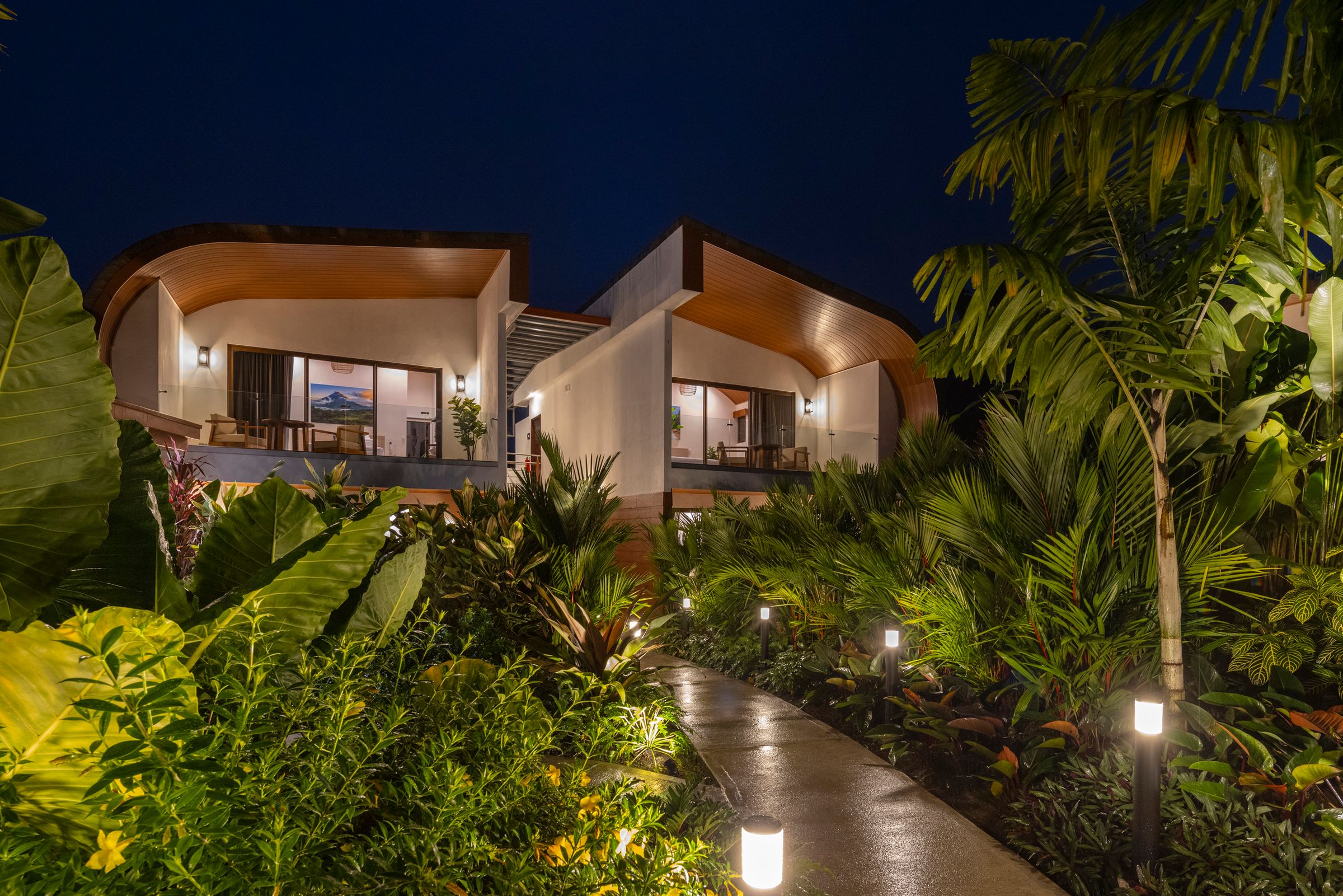 Fortuna Retreat villas lit up at night above the tropical garden path