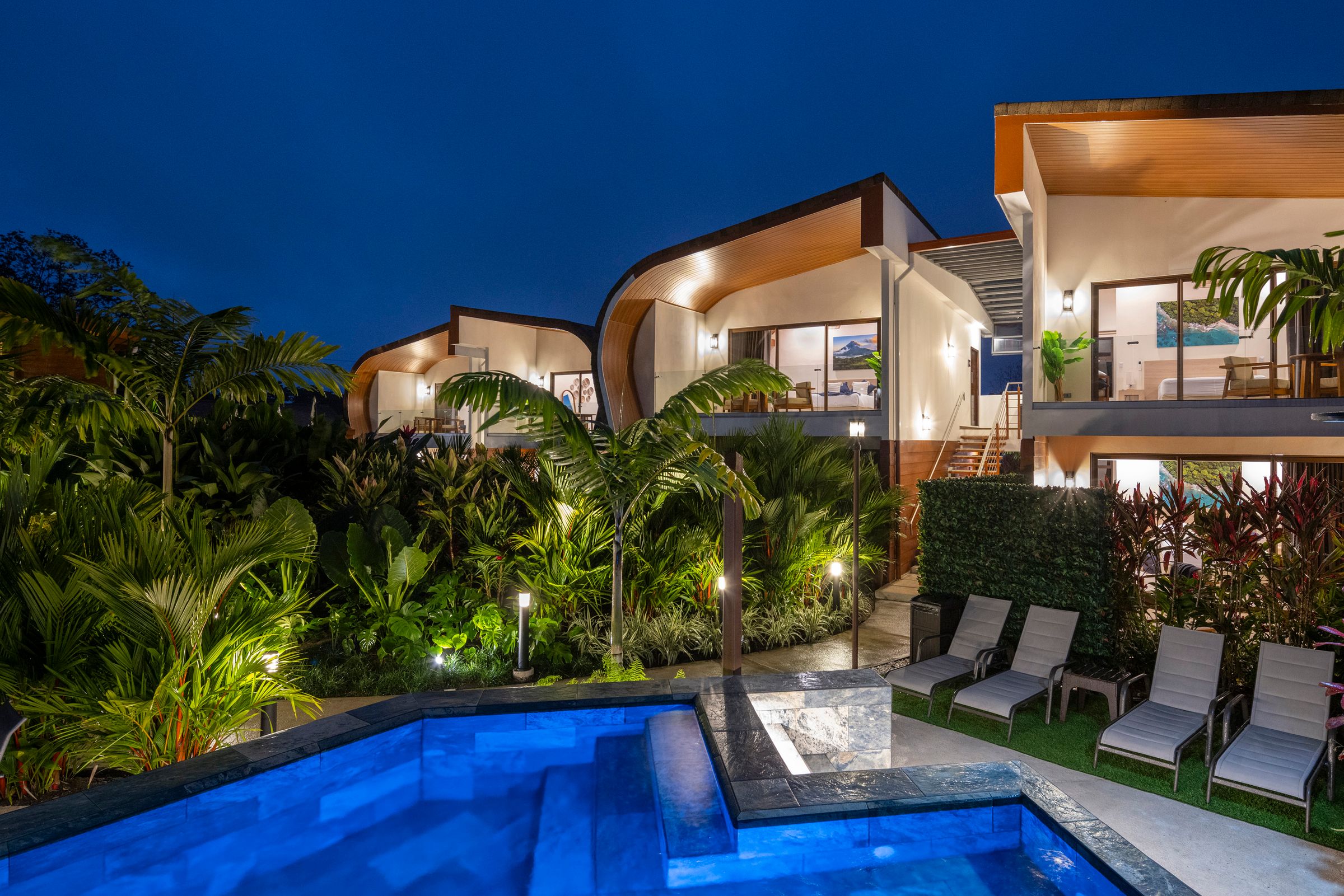 Fortuna Retreat villas and pool at blue hour, lit up among the tropical gardens